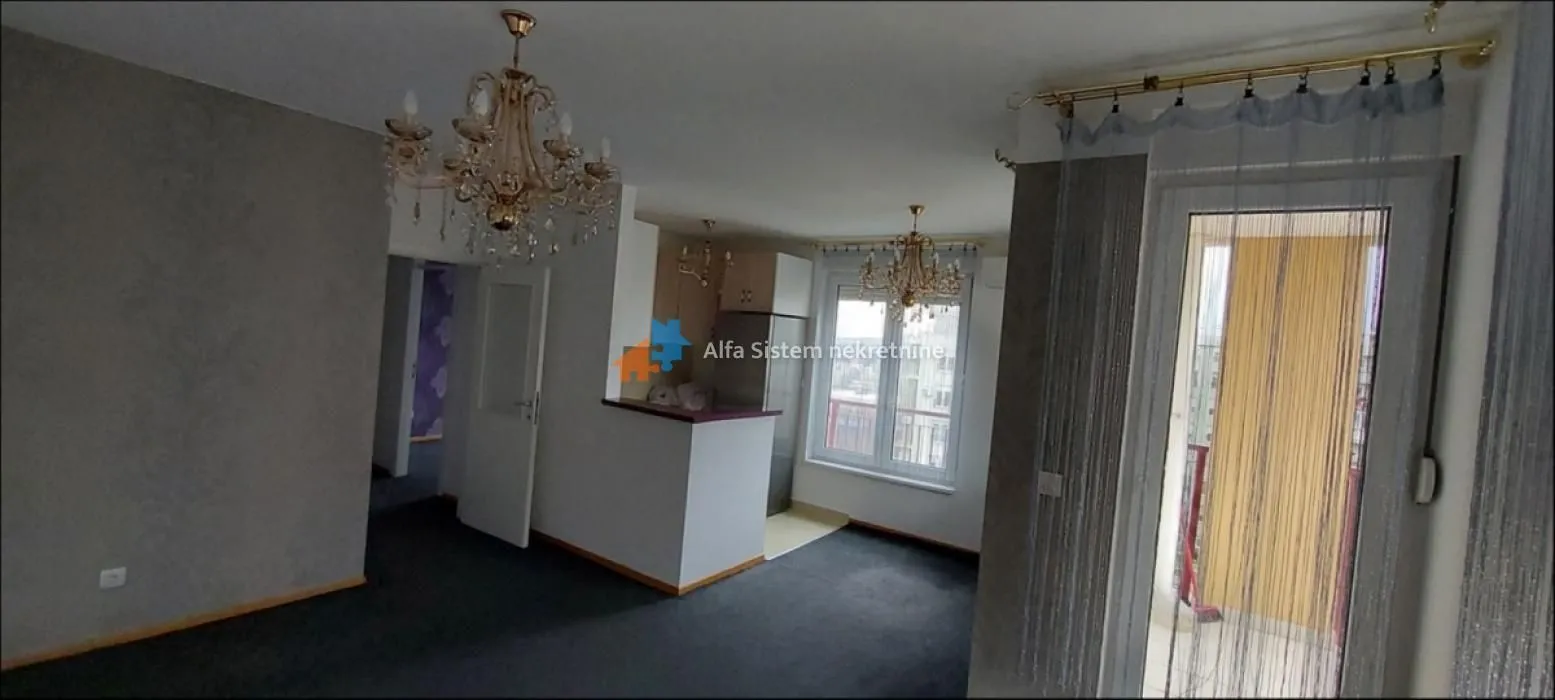 Dnevni boravak sa pogledom na deo kuhinje i izlazom na terasu.