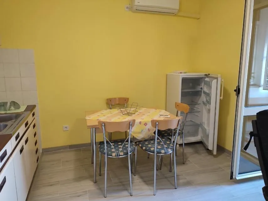 A kitchen with a dining table, chairs, and a refrigerator.