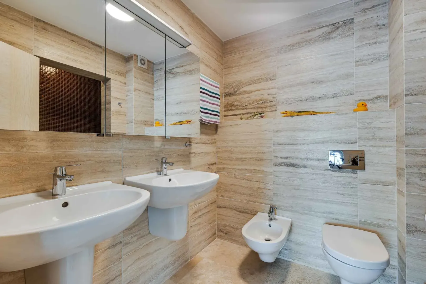 Moderno opremljeno kupatilo sa dva umivaonika, wc šoljom i bideom.