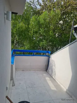 Smaller tiled balcony with a view of green trees. - image 8