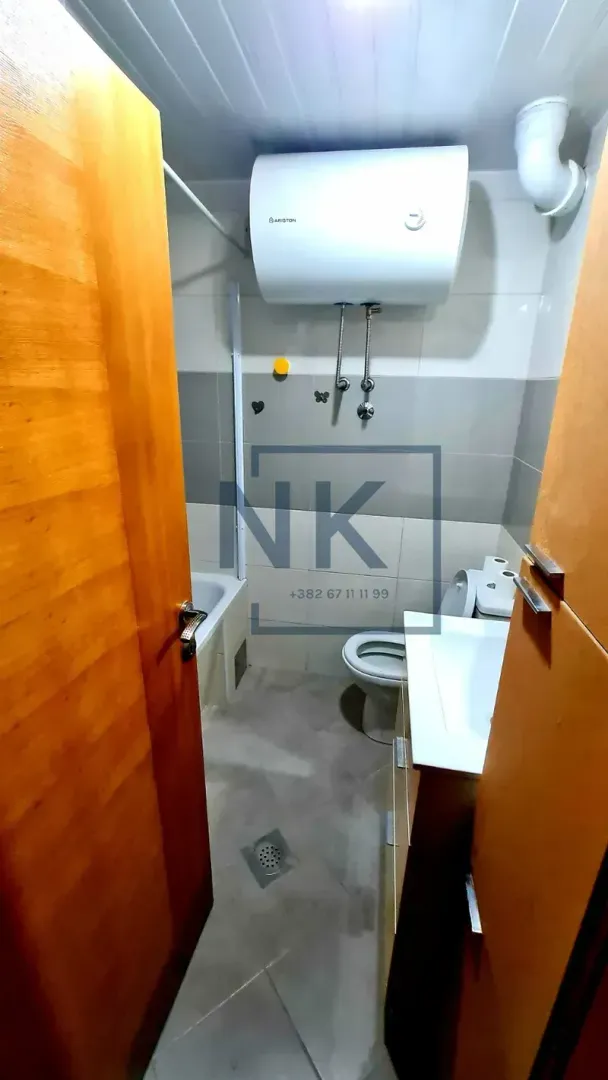 Manje kupatilo sa tuš kabinom, umivaonikom i bojlerom.