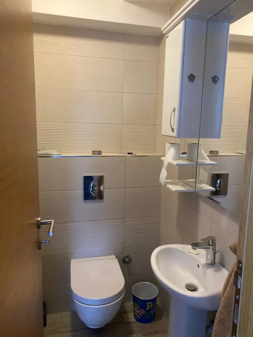 Manje kupatilo sa umivaonikom, šoljom i visećim ormarićem sa ogledalom.
