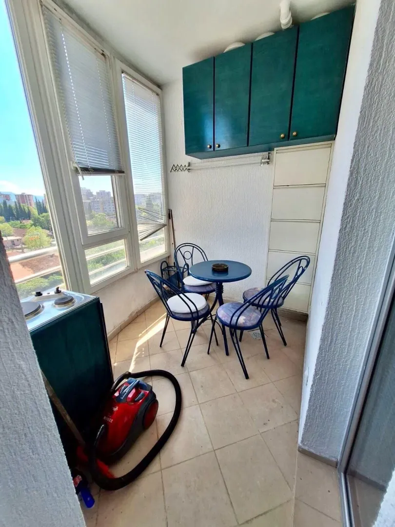 Enclosed balcony with seating furniture and storage units.