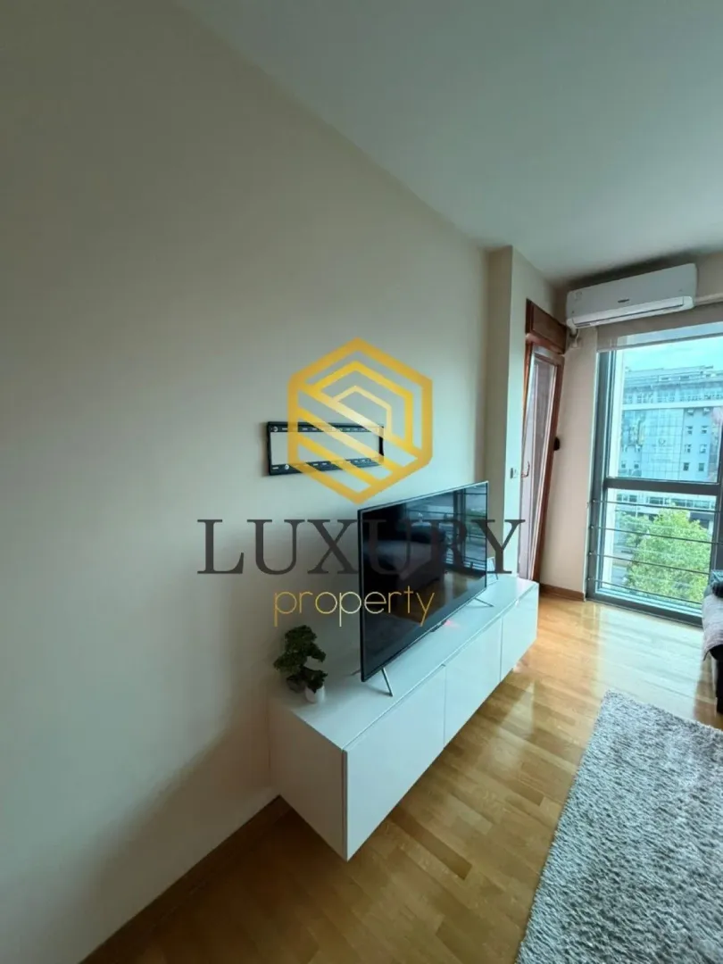 Dnevna soba sa televizorom i izlazom na terasu.