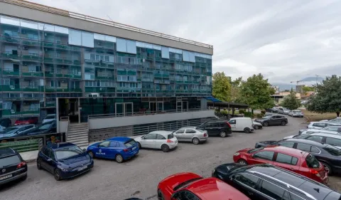 View of the exterior of the building with a parking lot and surrounding greenery. - image 13