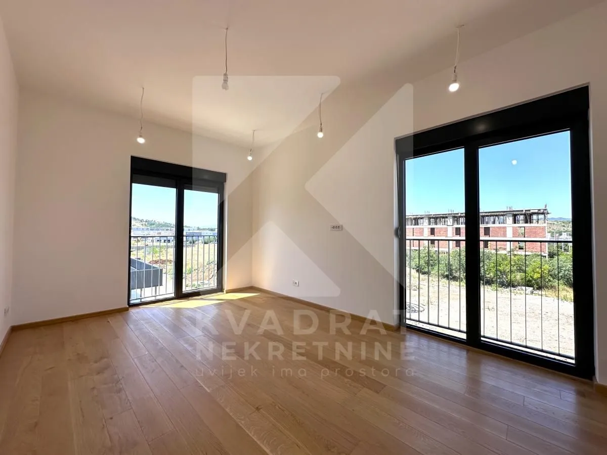 Empty room with parquet flooring and two balcony doors.
