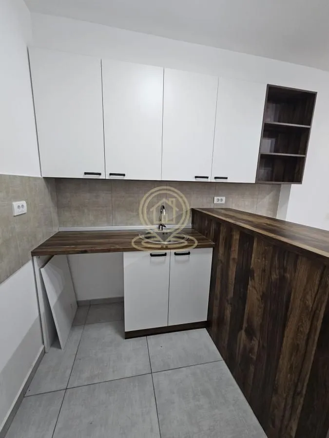 Small kitchen with white cabinets and a dark wood-patterned breakfast bar.