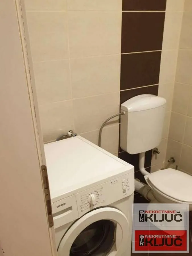Manje kupatilo sa WC šoljom i veš mašinom.