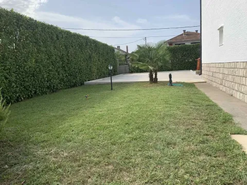 A landscaped yard with a lawn and hedge next to the house. - image 7
