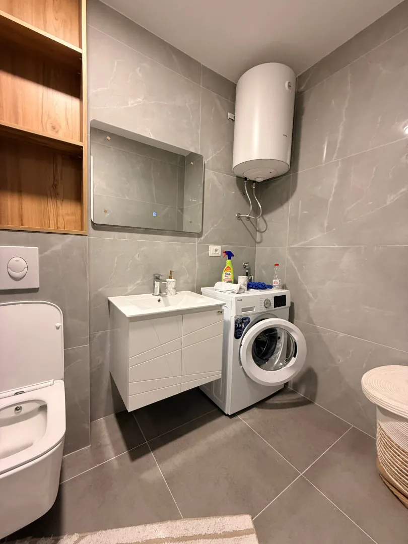 Moderne kupatilo sa umivaonikom, wc šoljom, bojlerom i veš mašinom.