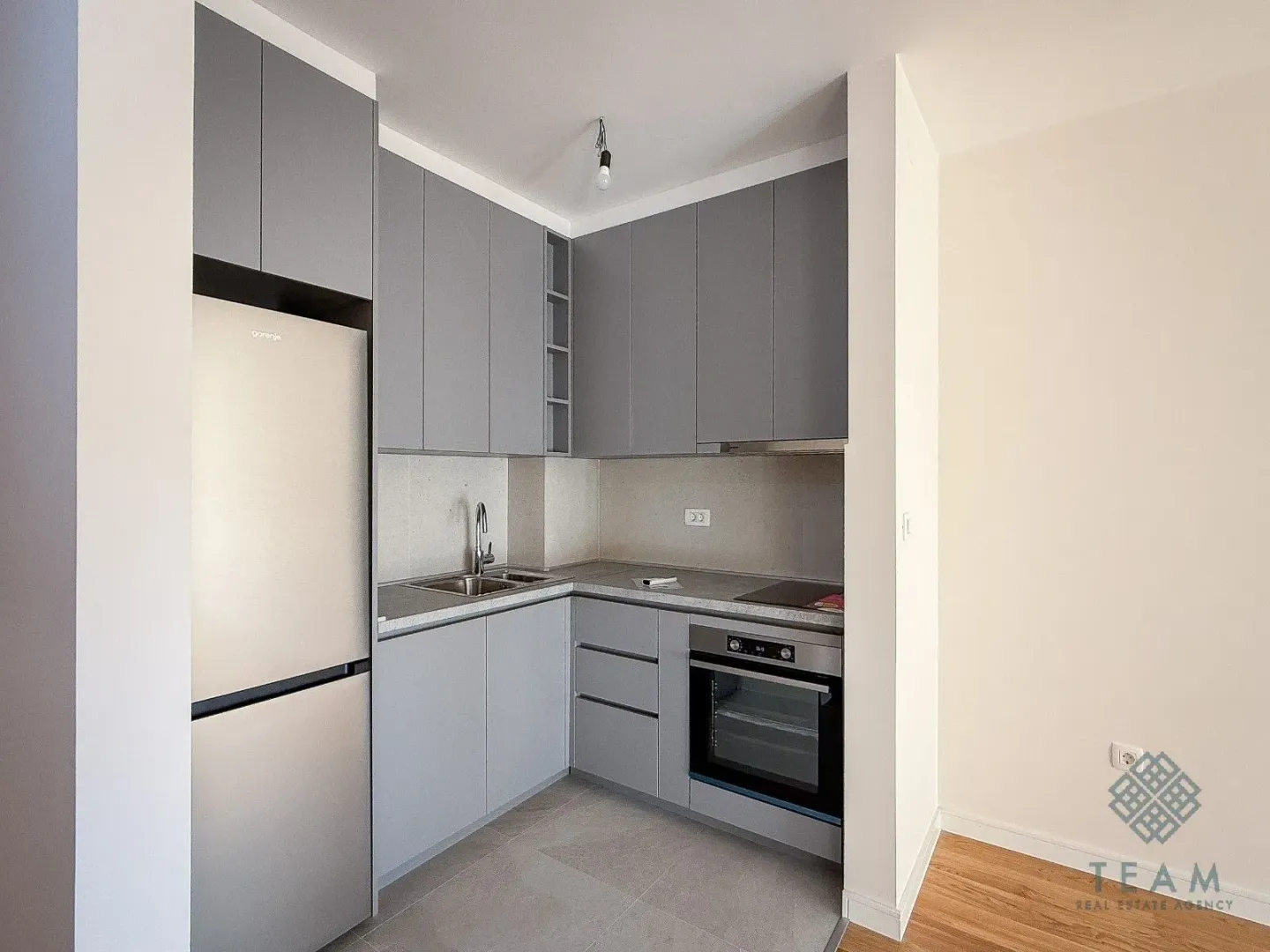 Small modern kitchen with grey cabinetry and built-in appliances.