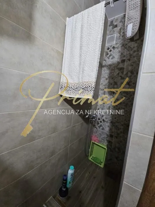 A view of the shower cabin in a tiled bathroom.