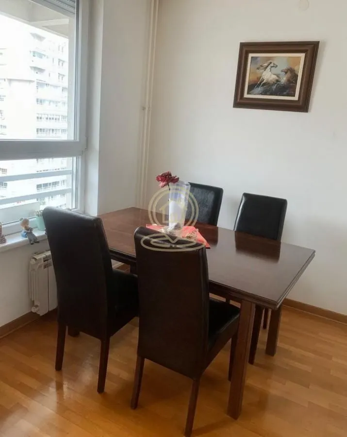 Trpezarija sa drvenim stolom i stolicama pored prozora.