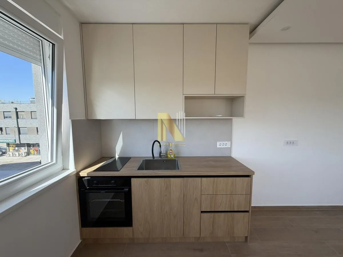 Small kitchen with wooden cabinets and a built-in oven next to the window.