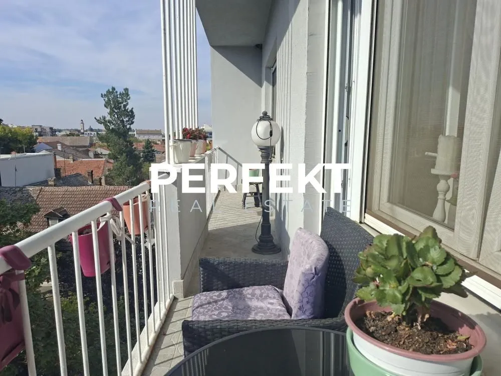 Uski namešteni balkon sa garniturom za sedenje i pogledom na grad.