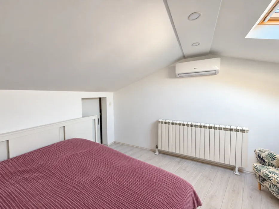 Attic bedroom with a double bed, air conditioning, and a skylight.