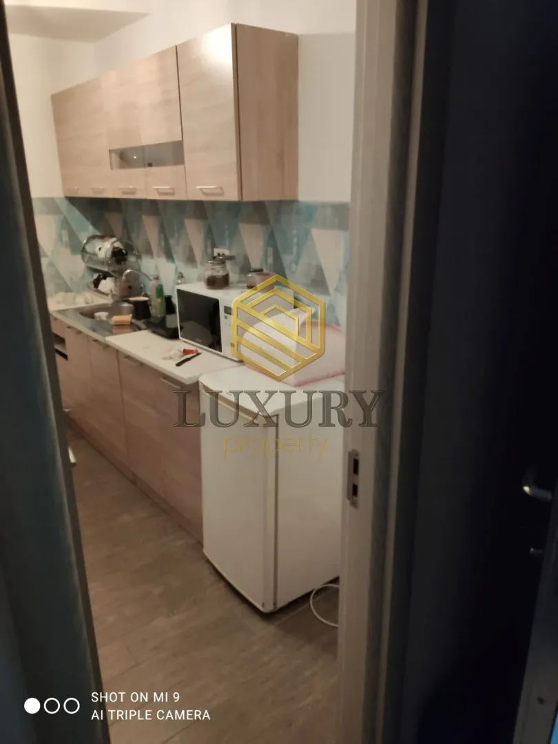 A view of a small kitchen with wooden elements through a doorway.