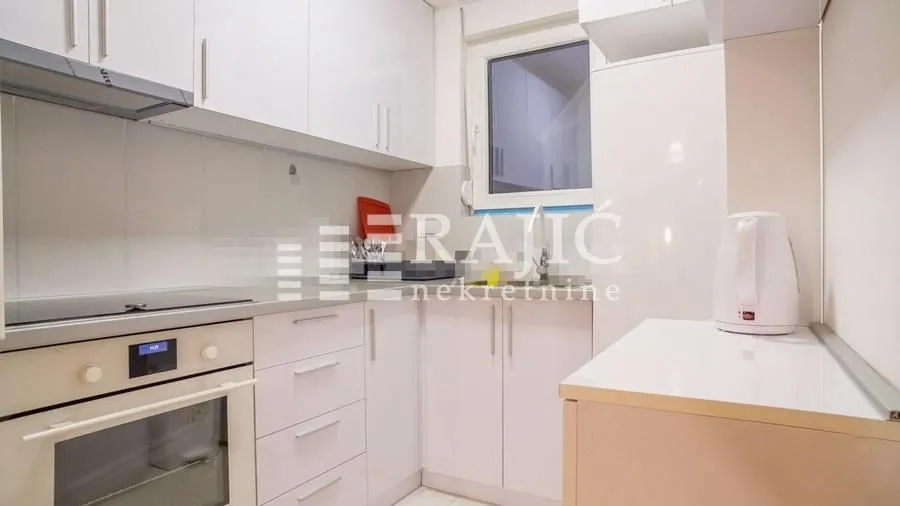 Small white kitchen with built-in cabinetry and a window.