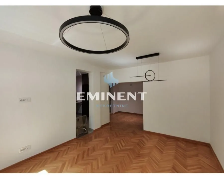 Empty room with parquet flooring and modern ceiling lighting.