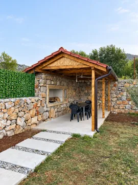 Covered gazebo with a barbecue grill and seating set in the yard. - image 5