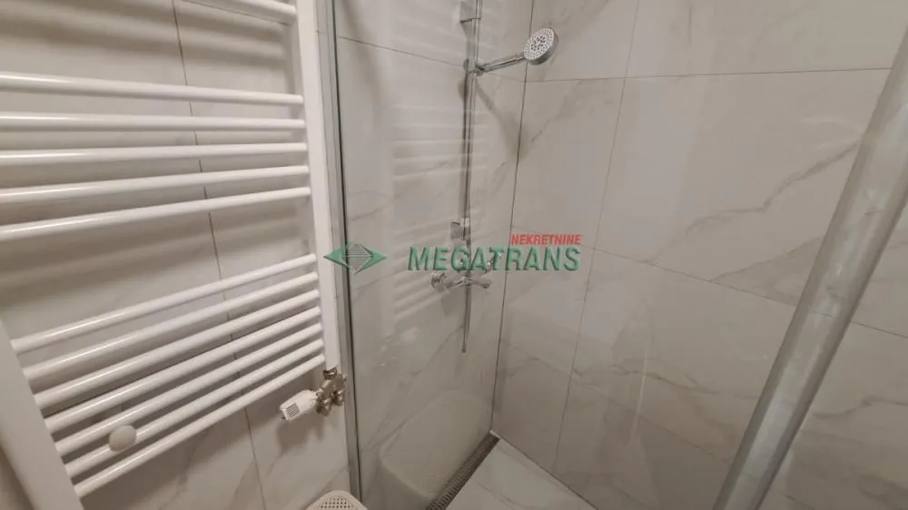 Pogled na tuš kabinu i radijator u kupatilu.