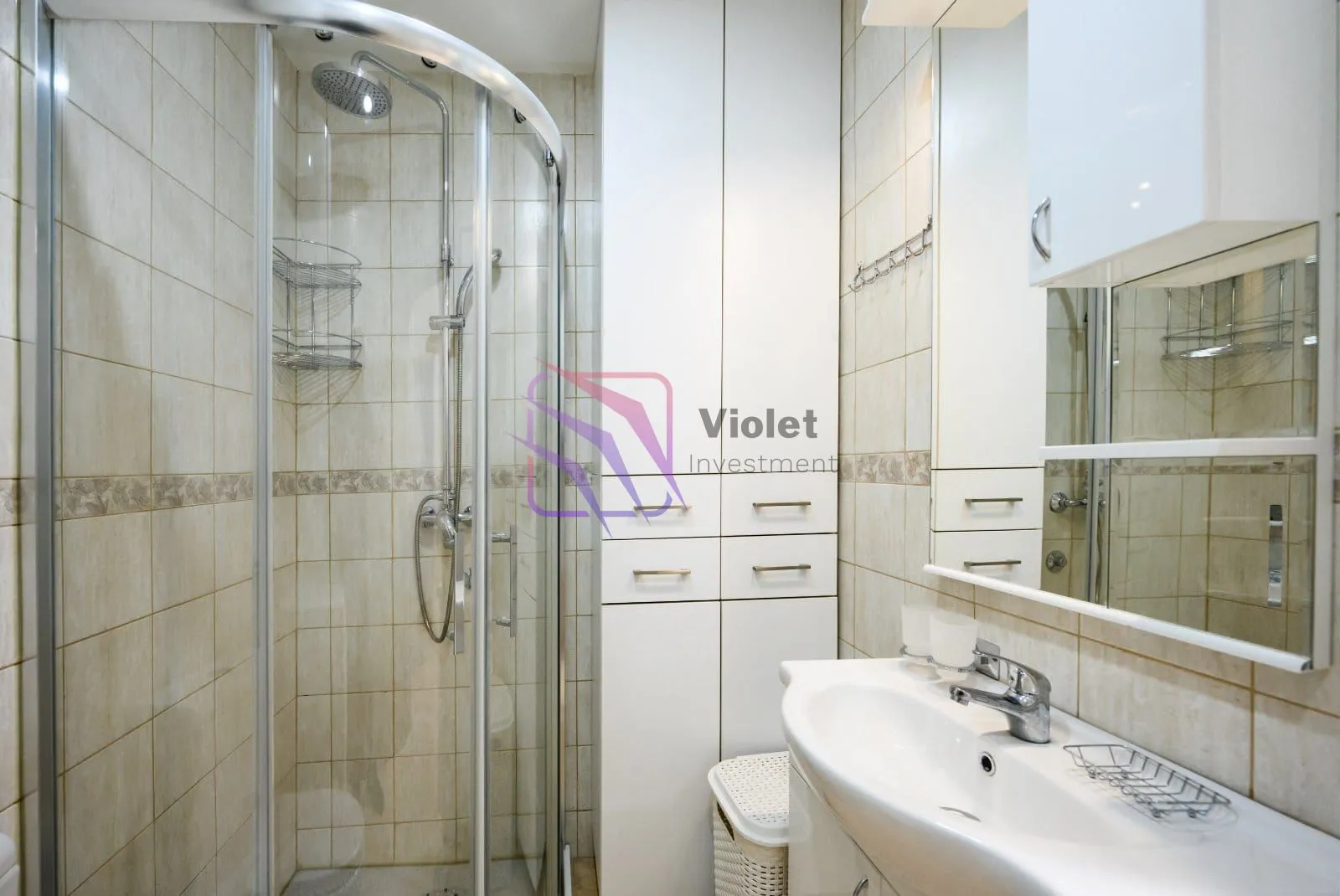 Bathroom with a shower cabin, washbasin, and built-in cabinet.