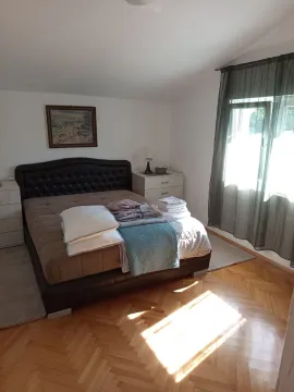 Spavaća soba sa bračnim krevetom, noćnim stočićem i prozorom sa zavjesama. - image 3