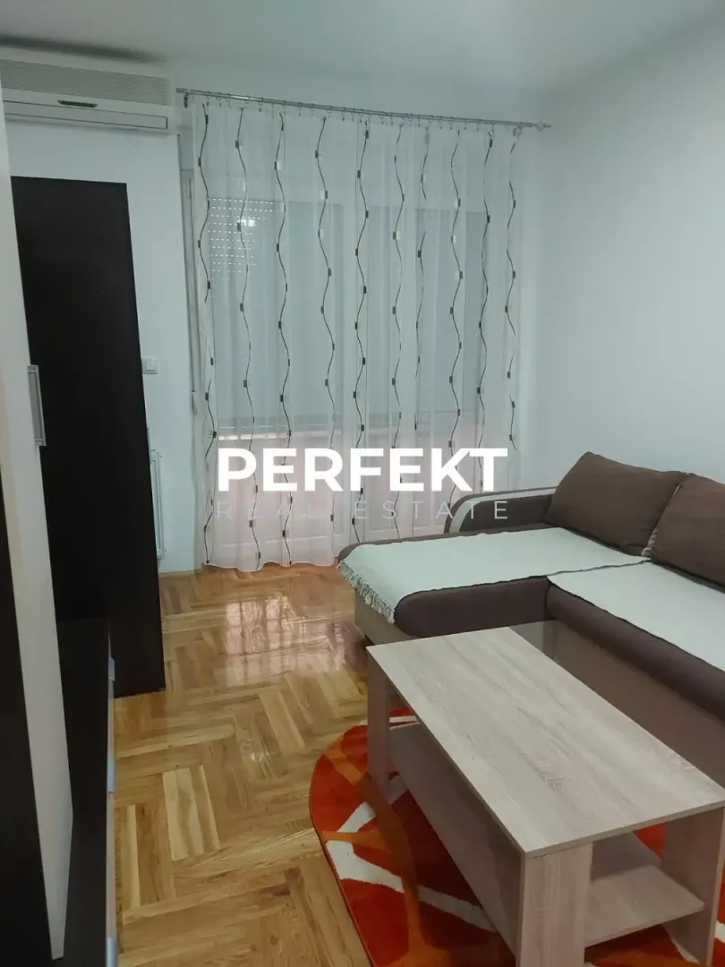 Living room with a sectional sofa, coffee table, and parquet flooring.