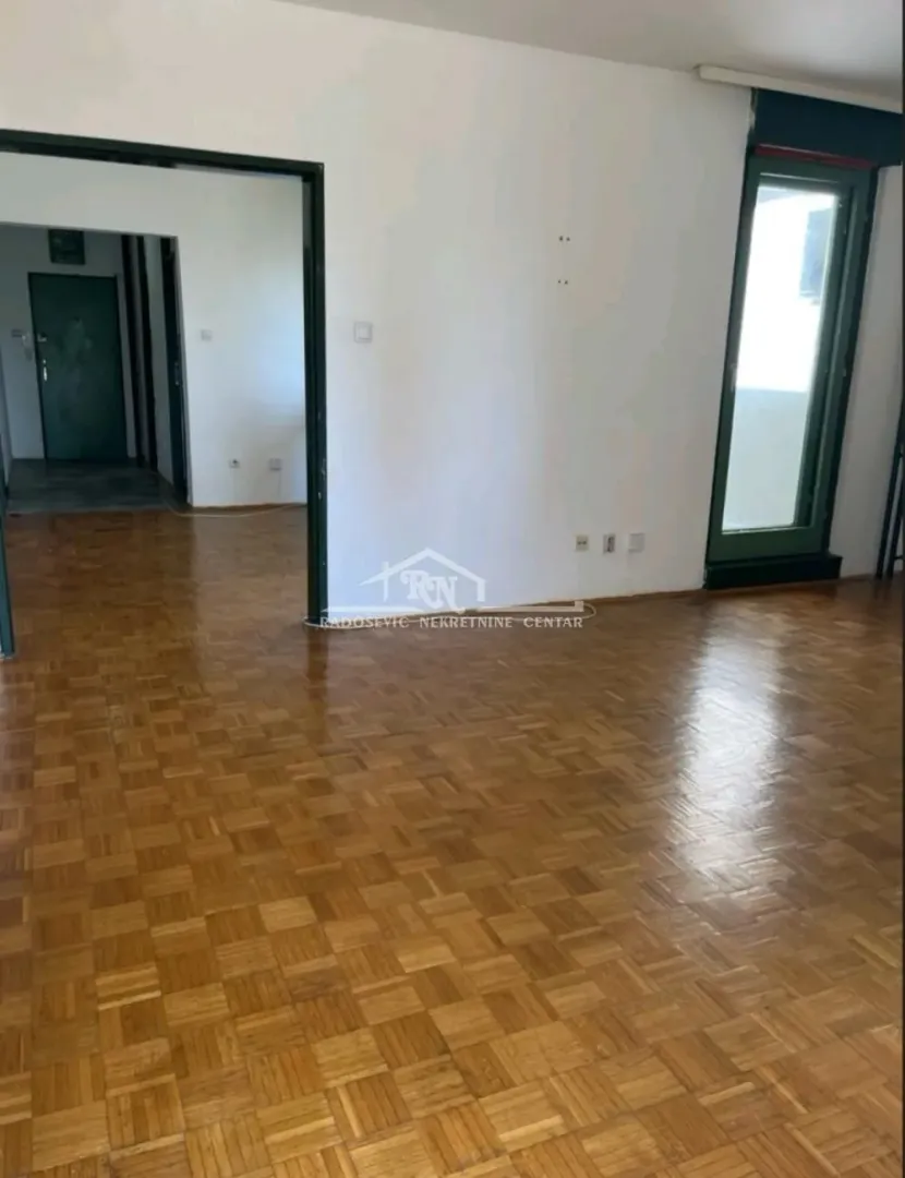 Empty room with parquet flooring and a doorway leading to the hallway.