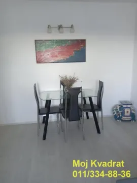 A dining table with chairs against a white wall with an artwork. - image 2