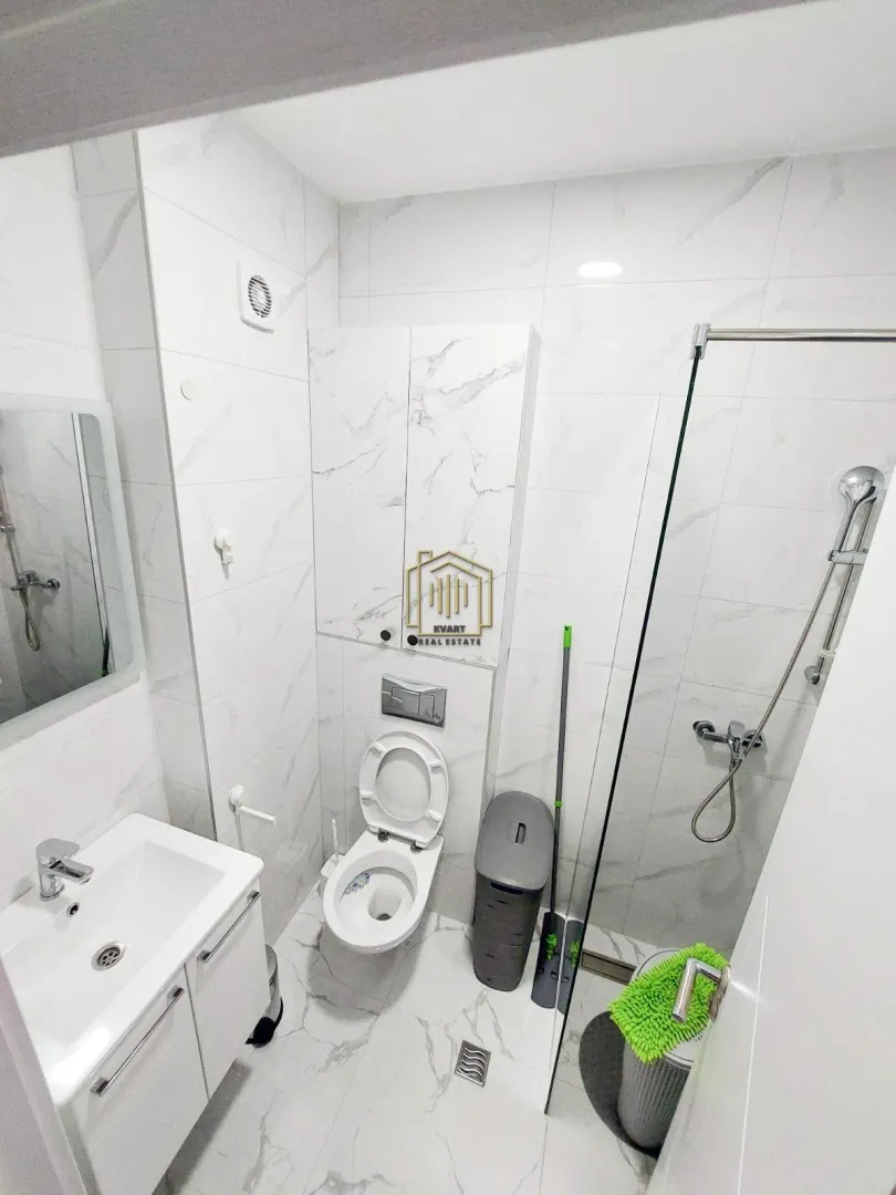 Modern bathroom with a walk-in shower, washbasin, and wall-mounted toilet.