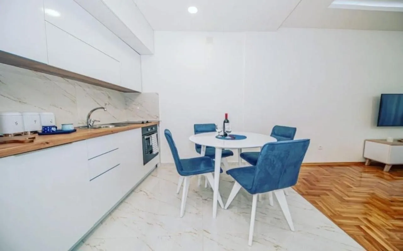 Modern white kitchen with a dining table and blue chairs.
