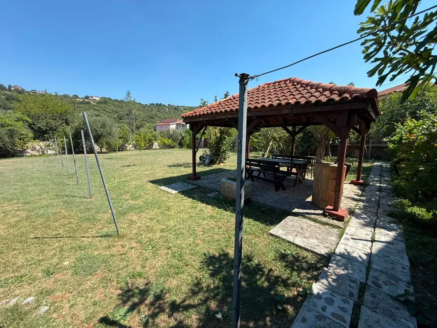 Spacious yard with a wooden gazebo and lawn.
