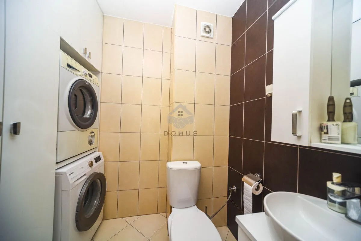 Bathroom with toilet, washbasin, and built-in washer and dryer.