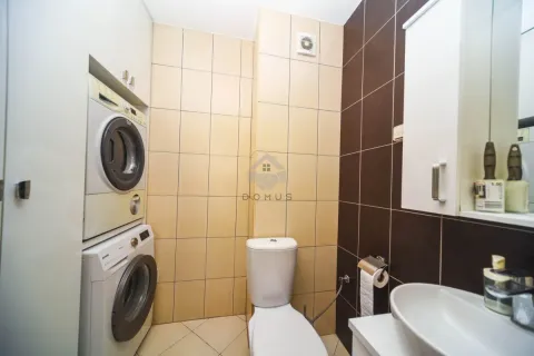 Bathroom with toilet, washbasin, and built-in washer and dryer. - image 8