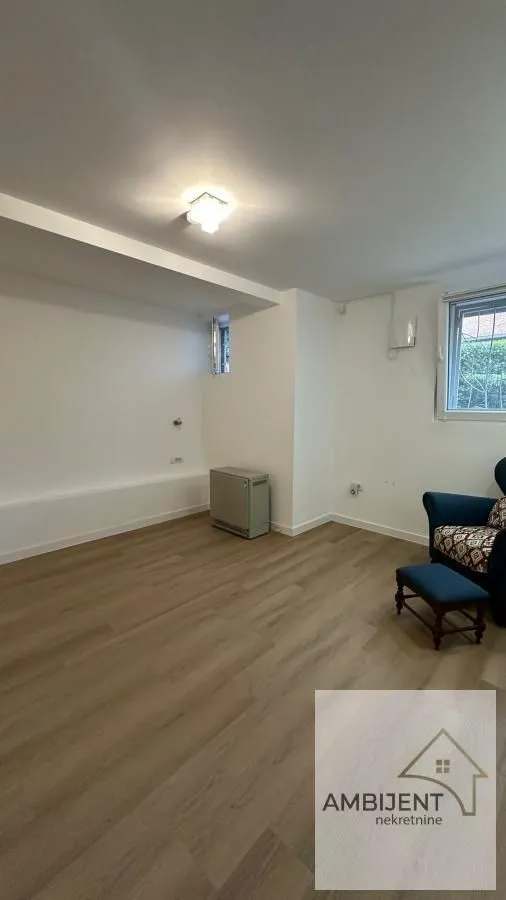 Small empty room with laminate flooring and a blue armchair.