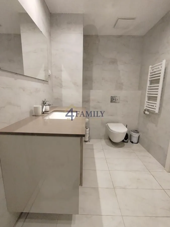 Modern bathroom with a sink and toilet tiled with light-colored tiles.