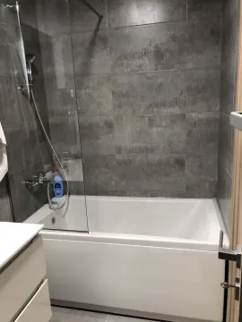 Modern bathroom with a bathtub and grey tiles. - image 19