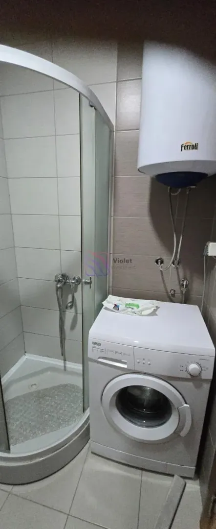 Bathroom with a shower cabin, washing machine, and water heater.
