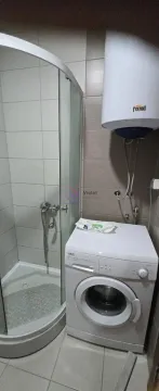 Bathroom with a shower cabin, washing machine, and water heater. - image 5