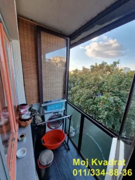 Manji zatvoreni balkon sa pogledom na zelenilo i sušačem za veš. - image 3
