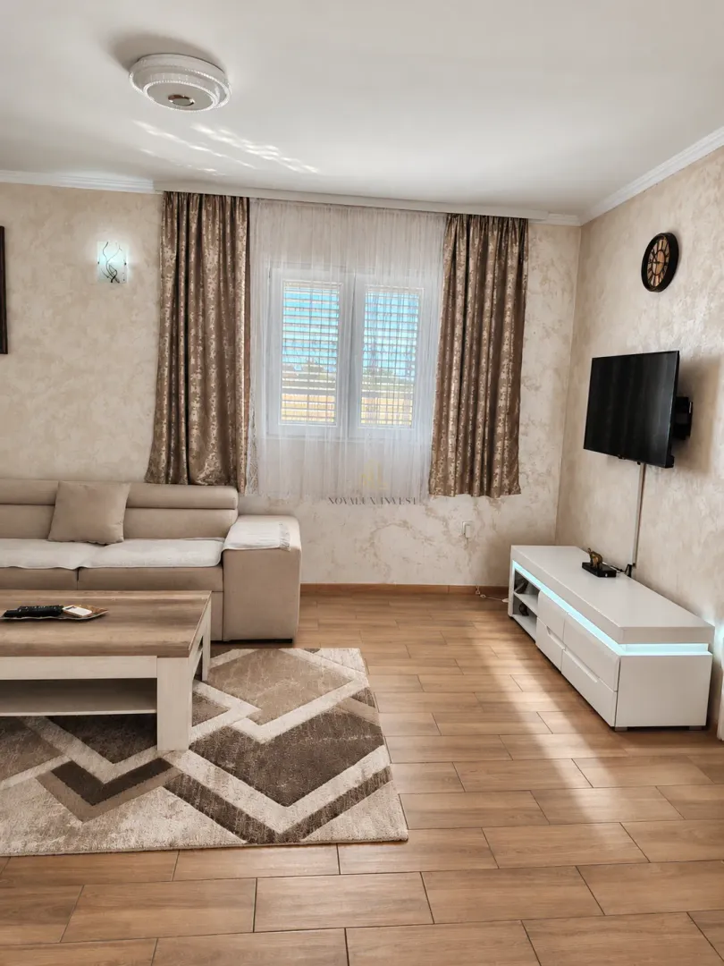 Living room with a sofa, coffee table, TV, and a window with curtains.