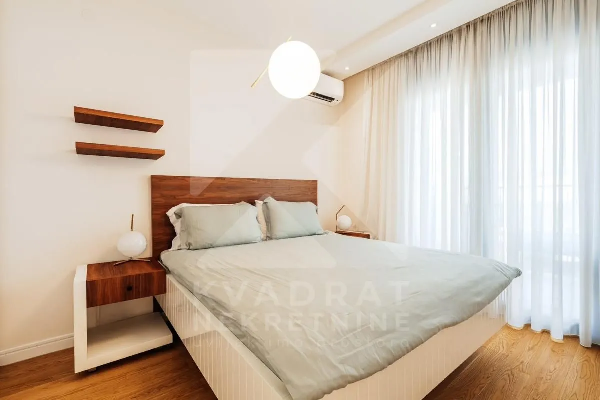 Modern bedroom with a double bed, bedside tables and wooden flooring.