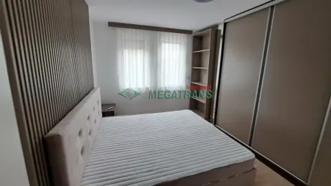 Nameštena spavaća soba sa bračnim krevetom, velikim ormanom i drvenim zidnim panelom. - image 11