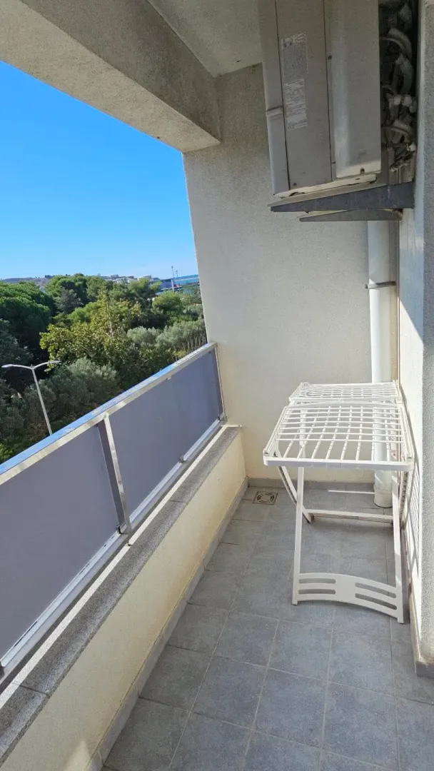 Manji svijetli balkon sa sušilicom za veš i klima uređajem.