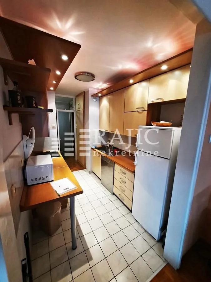 Compact equipped kitchen with a white refrigerator and wooden cabinets.