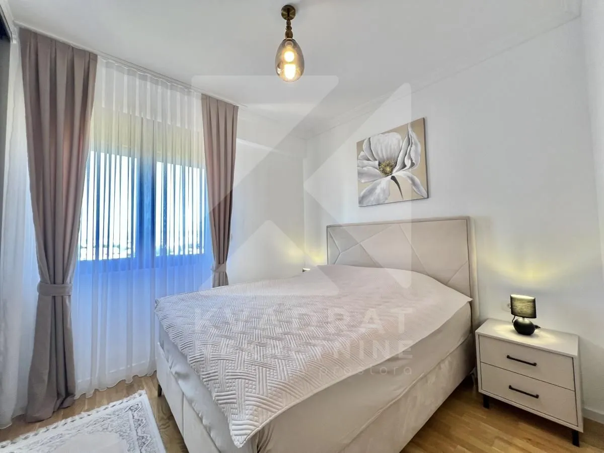 Furnished bedroom with a double bed, nightstand, and window with curtains.