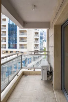 Unfurnished balcony with a glass railing and a view of surrounding buildings. - image 7