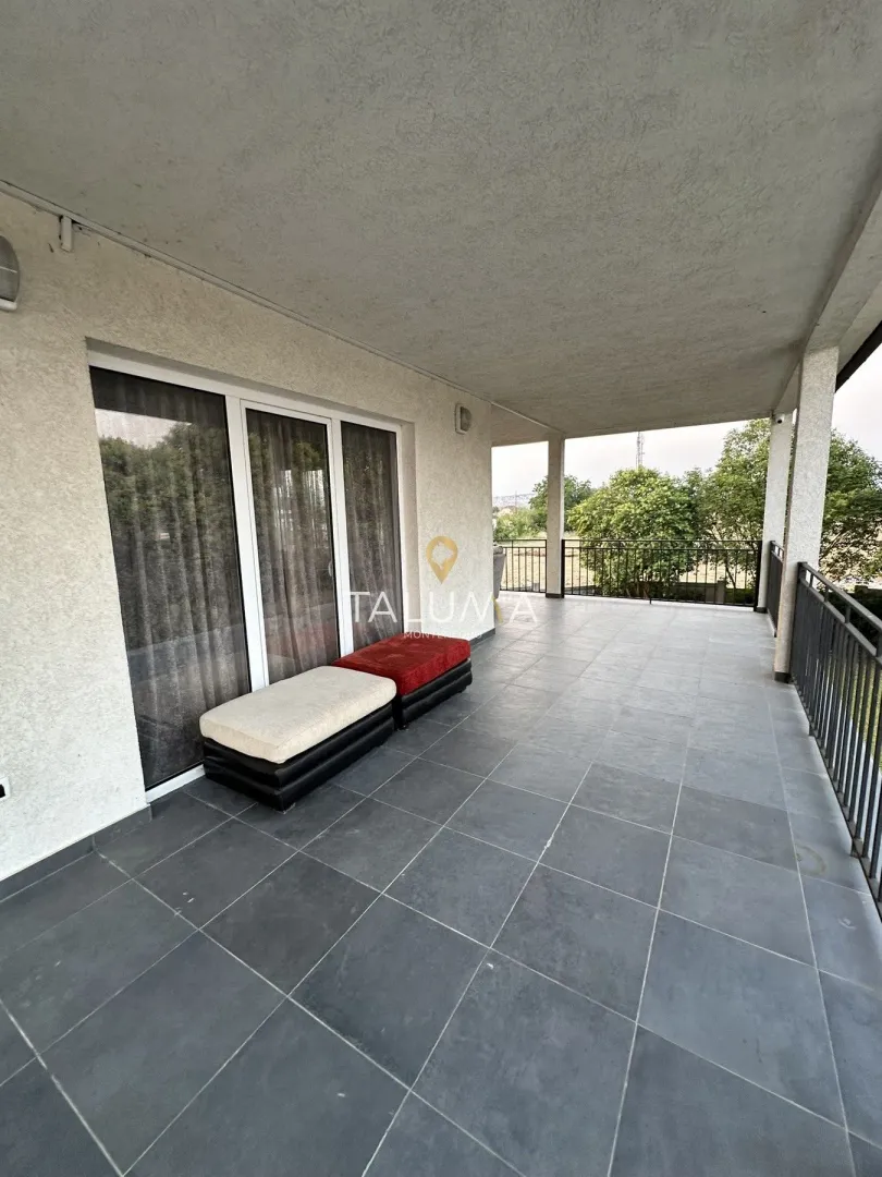 Spacious covered terrace with ceramic tiles and railing.