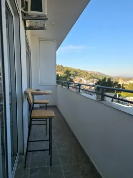 Dugi balkon sa barskim stolom i stolicama i pogledom na grad. - image 10